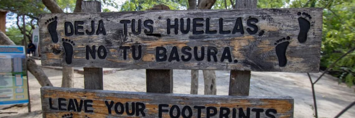 Wooden sign promoting nature preservation in a lush outdoor area.